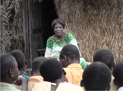 Hudolo Atosu, the storyteller of Jealous Twins, before her house.